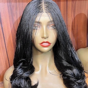 May include: A black wig with micro braids and long, wavy ends. The wig is styled on a mannequin head with a neutral skin tone and red lipstick. The hair is parted in the middle and has a natural-looking hairline.