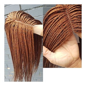 May include: A brown braided wig with a lace front. The wig is made of synthetic hair and is styled in a long, straight braid.