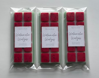 May include: Three packages of watermelon scented wax melts. Each package contains six individual wax melts and has a label that reads "Watermelon Wedges" with the company name "Alice Wax Works".