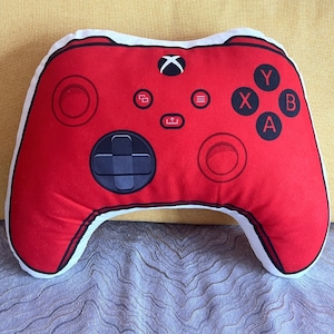 May include: Red gaming controller shaped pillow with white accents and buttons labeled X, Y, A, and B.