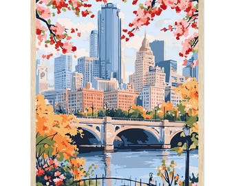 May include: A framed cityscape painting featuring a bridge over a river, with buildings in the background. The artwork has a light wood frame and depicts a scene with blue, orange, and pink hues, with cherry blossoms in the foreground.