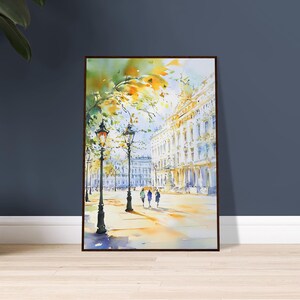 Op de afbeelding: Een aquarel schilderij van een stadstraat met gebouwen, bomen en mensen die lopen. De gebouwen zijn geschilderd in een lichtgele kleur, en de bomen zijn geschilderd in een groene en gele kleur. De mensen zijn geschilderd in een blauwe en bruine kleur.