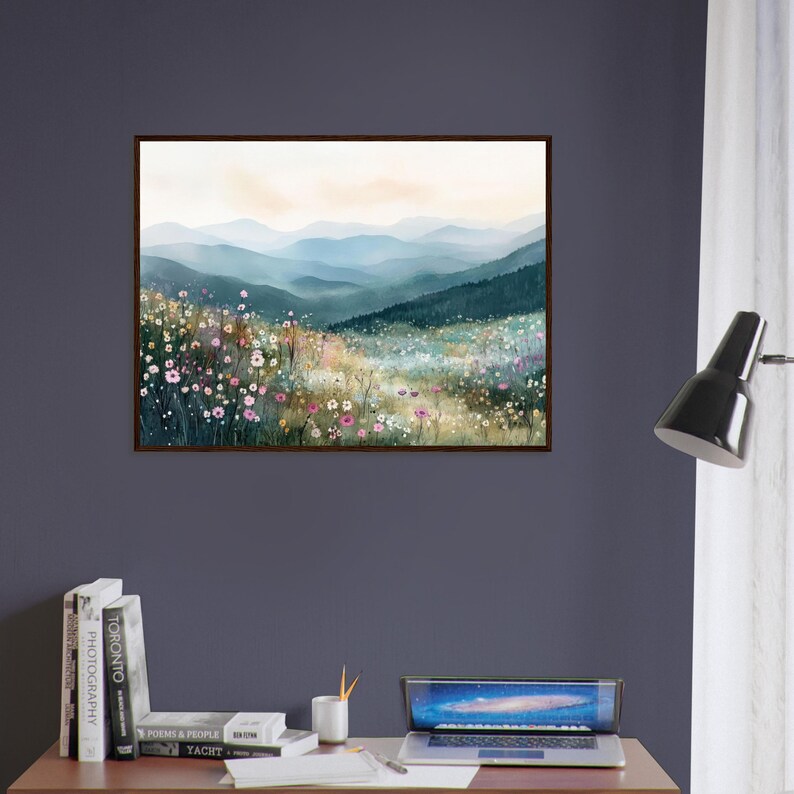 May include: A framed landscape wall art print featuring a watercolor-style painting of a wildflower meadow in the foreground with rolling blue and green mountain ranges in the distance under a soft, pale, light-filled sky.