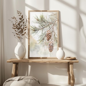 May include: A framed watercolor painting of a pine branch with three pine cones hanging from it. The background is a soft, watercolor wash of green and white.