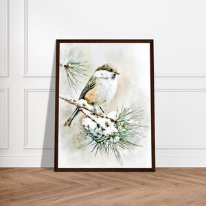 May include: A framed print featuring a small bird perched on a snow-covered pine branch. The bird has a mix of brown, white, and gray feathers. The artwork has a watercolor effect, with a soft, neutral background and a dark brown frame.