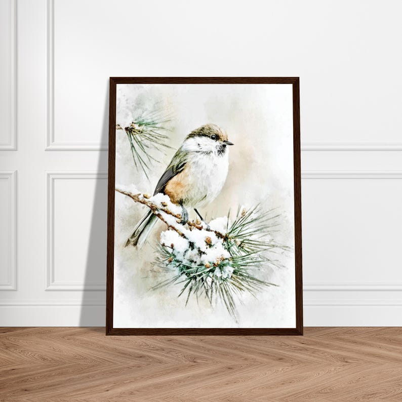 May include: A framed print featuring a small bird perched on a snow-covered pine branch. The bird has a mix of brown, white, and gray feathers. The artwork has a watercolor effect, with a soft, neutral background and a dark brown frame.