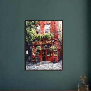 May include: A framed painting of The Temple Bar in Dublin, featuring a vibrant red facade, large windows, and green foliage. The storefront displays the text THE TEMPLE BAR in gold lettering above the entrance, set against a cobblestone street.