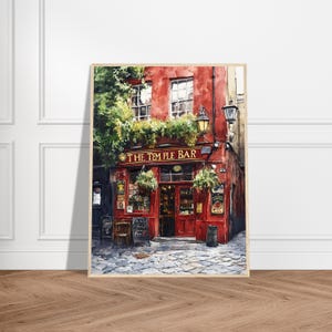 May include: A framed watercolor painting of The Temple Bar in Dublin, featuring a vibrant red facade, green hanging plants, dark window frames, and a cobblestone street. The sign above the entrance clearly displays the text THE TEMPLE BAR.