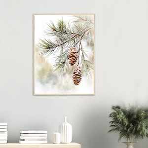 May include: A close-up of a pine branch with two brown pine cones hanging from it. The background is a soft, blurred watercolor wash of green and white.