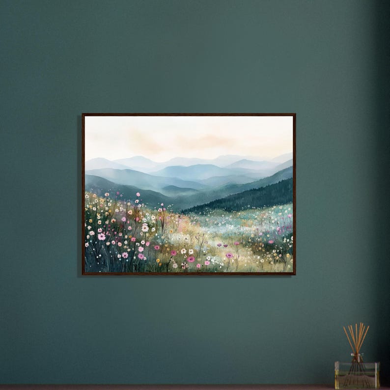 May include: A framed landscape wall art print featuring a watercolor painting of a mountain range in soft blue and grey tones, overlooking a vibrant meadow filled with small pink, white, and yellow wildflowers under a pale sky.