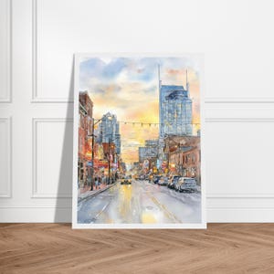 May include: A watercolor painting of a city street at sunset, featuring tall buildings, glowing neon signs, and cars driving along the road. The sky is painted in soft shades of yellow, orange, and blue, reflecting light onto the wet pavement.