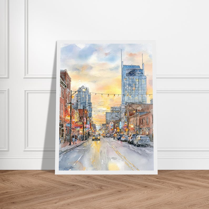 May include: A watercolor painting of a city street at sunset, featuring tall buildings, glowing neon signs, and cars driving along the road. The sky is painted in soft shades of yellow, orange, and blue, reflecting light onto the wet pavement.