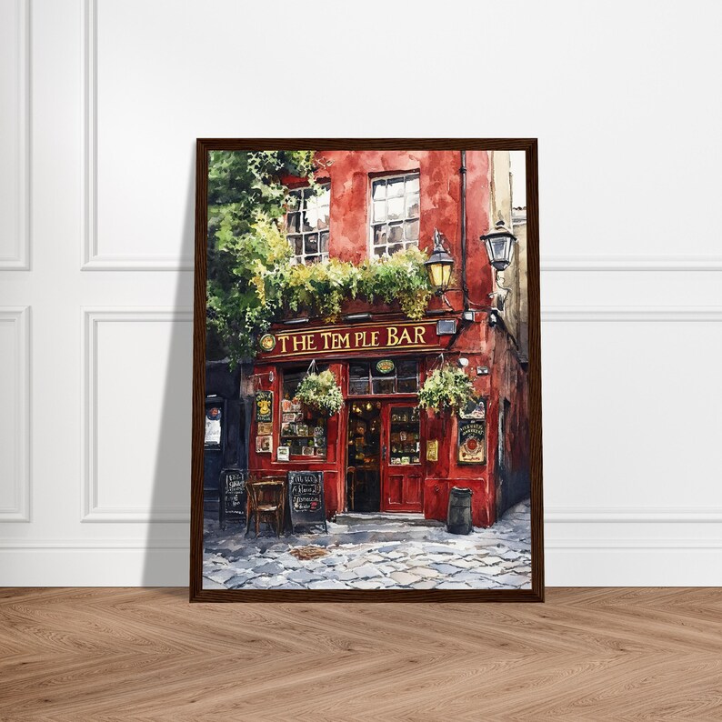 May include: A framed painting of The Temple Bar, featuring a vibrant red facade with gold lettering, large windows, and lush green foliage hanging above the entrance. The scene includes a cobblestone street, a dark trash bin, and wall signs.