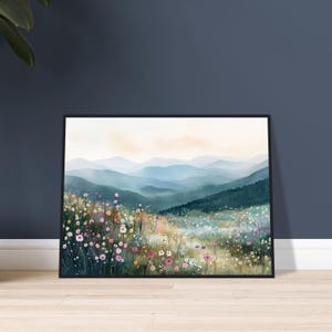 May include: A framed landscape print featuring a field of wildflowers in shades of pink, white, and yellow in the foreground, with layers of blue and green misty mountains receding into the distance under a soft, pale sky.