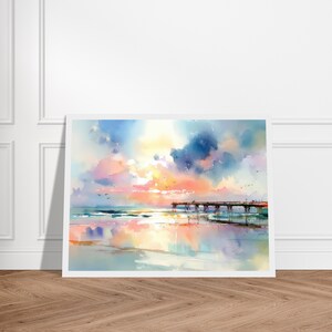 Puede incluir: Una pintura de acuarela de un muelle de madera que se extiende hacia el oc&eacute;ano al atardecer. El cielo presenta suaves mezclas de nubes rosas, naranjas y azules, con los colores reflej&aacute;ndose en la arena mojada y el agua tranquila.