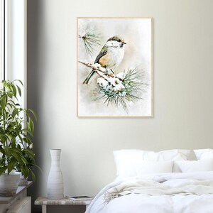 May include: A framed watercolor print of a small bird perched on a snow-covered pine branch. The bird has a brown head, white chest, and tan back. The artwork is set against a soft, neutral background, creating a serene and naturalistic scene.