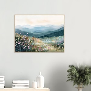 May include: A rectangular wall art print featuring a landscape painting of a wildflower meadow in the foreground with pink, white, and yellow blossoms. In the background, layers of blue and green mountains fade into a soft sky.