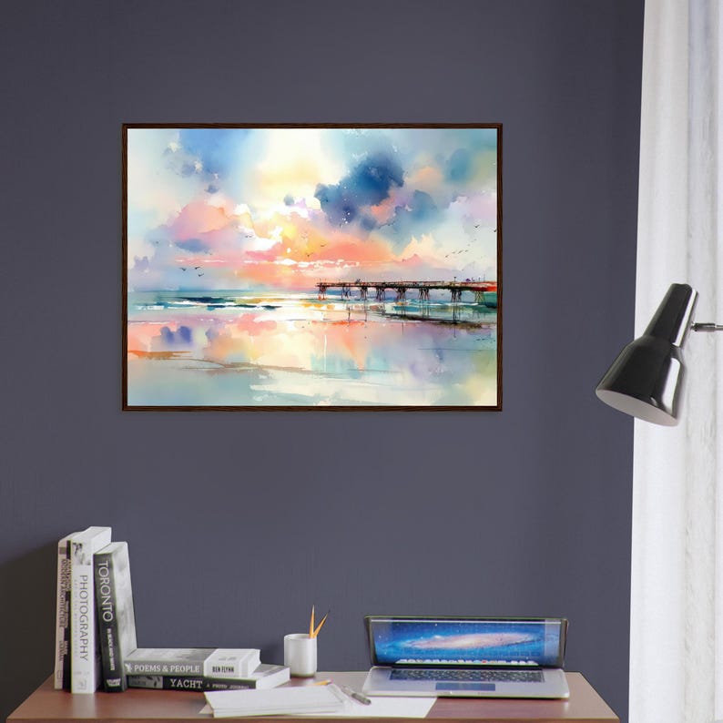 Puede incluir: Una pintura de acuarela enmarcada que representa un muelle de madera que se extiende hacia un oc&eacute;ano tranquilo bajo un cielo vibrante lleno de nubes suaves en tonos rosa, naranja, amarillo y azul, con la escena reflejada en la arena mojada.