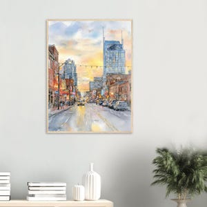 May include: A watercolor painting of a city street at sunset, featuring tall buildings, glowing streetlights, and cars driving along a road. The sky is a blend of soft yellow, orange, and blue hues, reflecting light onto the wet pavement below.