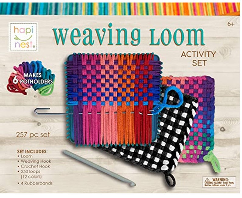Puede incluir: Un conjunto de actividades de tejido con hilo de colores y un telar para hacer 6 agarraderas. El conjunto incluye un gancho de tejido, un gancho de ganchillo, 250 bucles en 12 colores y 4 gomas el&aacute;sticas. La caja dice "hapi nest. weaving loom activity set".