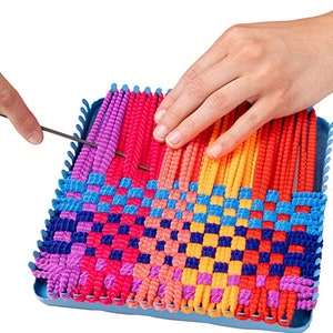 Puede incluir: Un telar de pl&aacute;stico azul con hilo de colores tejido en un patr&oacute;n de cuadros. El telar se est&aacute; utilizando para crear un proyecto tejido de colores.