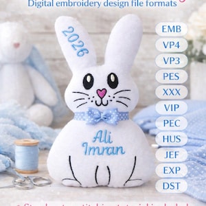 Puede incluir: Conejo de peluche blanco con detalles bordados, incluyendo el texto "2026" en una oreja y "Ali Imran" en el cuerpo. Tiene una pajarita azul y una nariz de corazón rosa. La imagen también incluye texto sobre formatos de archivo de diseño de bordado digital y tamaños de aro.