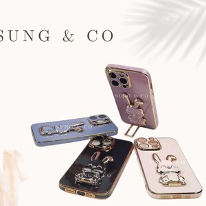 May include: Four different phone cases with a gold trim and a 3D animal design. The cases are pink, blue, black, and white. Each case has the text "SUNG & CO" on the back.