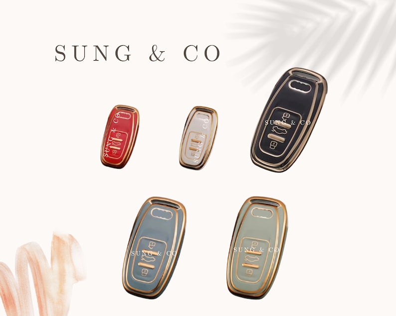 May include: Five key-shaped ceramic ornaments in different colors. The ornaments are red, white, black, light blue, and dark blue. Each ornament has a gold outline and the text "SUNG & CO" printed on it.