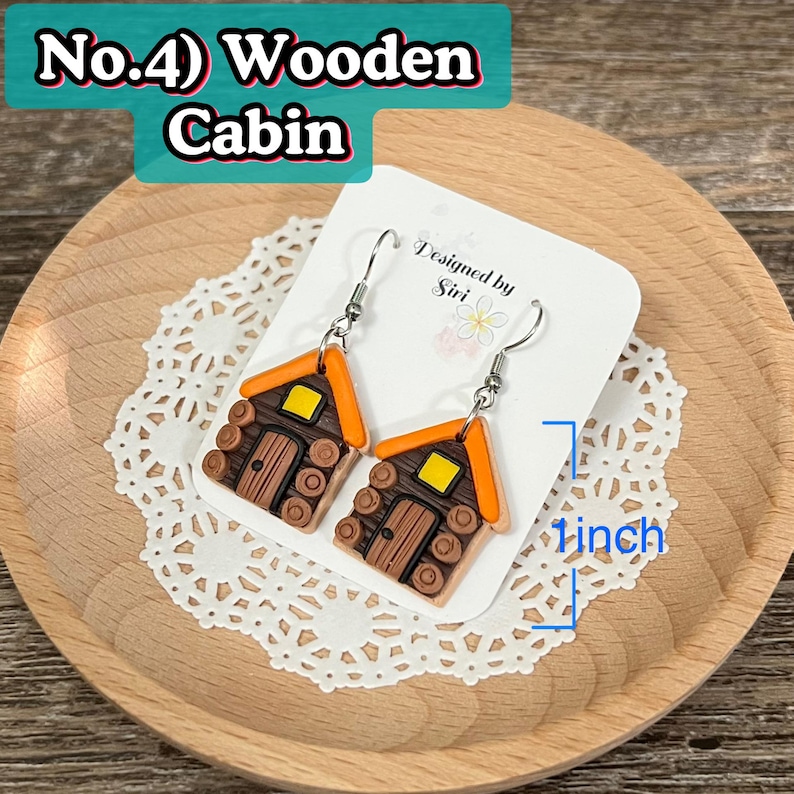 May include: A pair of dangle earrings shaped like miniature wooden cabins. The cabins are brown with orange roofs and yellow windows. The earrings are approximately 1 inch in length and hang from silver-colored hooks. The text "No.4) Wooden Cabin" is visible.