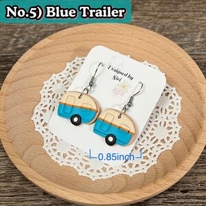 May include: Blue trailer earrings with silver hooks. The earrings are shaped like miniature trailers, featuring a blue body, tan roof, and black wheels. The earrings are approximately 0.85 inches in length. The text "No.5) Blue Trailer" is at the top.