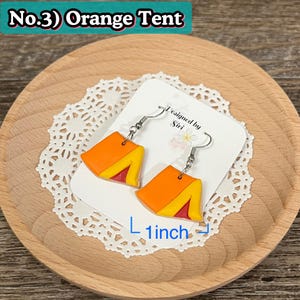 May include: Orange tent-shaped earrings with yellow and red accents, approximately 1 inch in length. The earrings are on a white card with the text "Designed by Siri". The text "No.3) Orange Tent" is at the top.