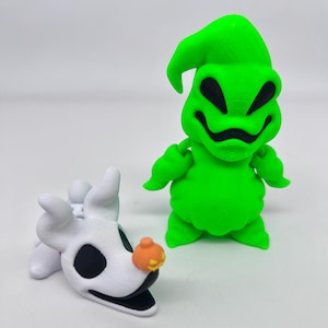 May include: A green Oogie Boogie figure and a white Zero figure with a pumpkin nose. The Oogie Boogie figure has a smiling face and is standing upright. The Zero figure is lying down with a black mouth and eye sockets.