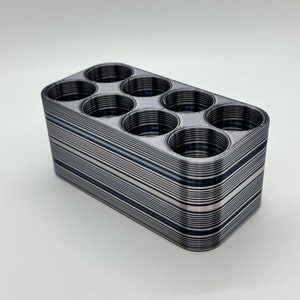 May include: A black and white striped plastic organizer with eight round compartments.