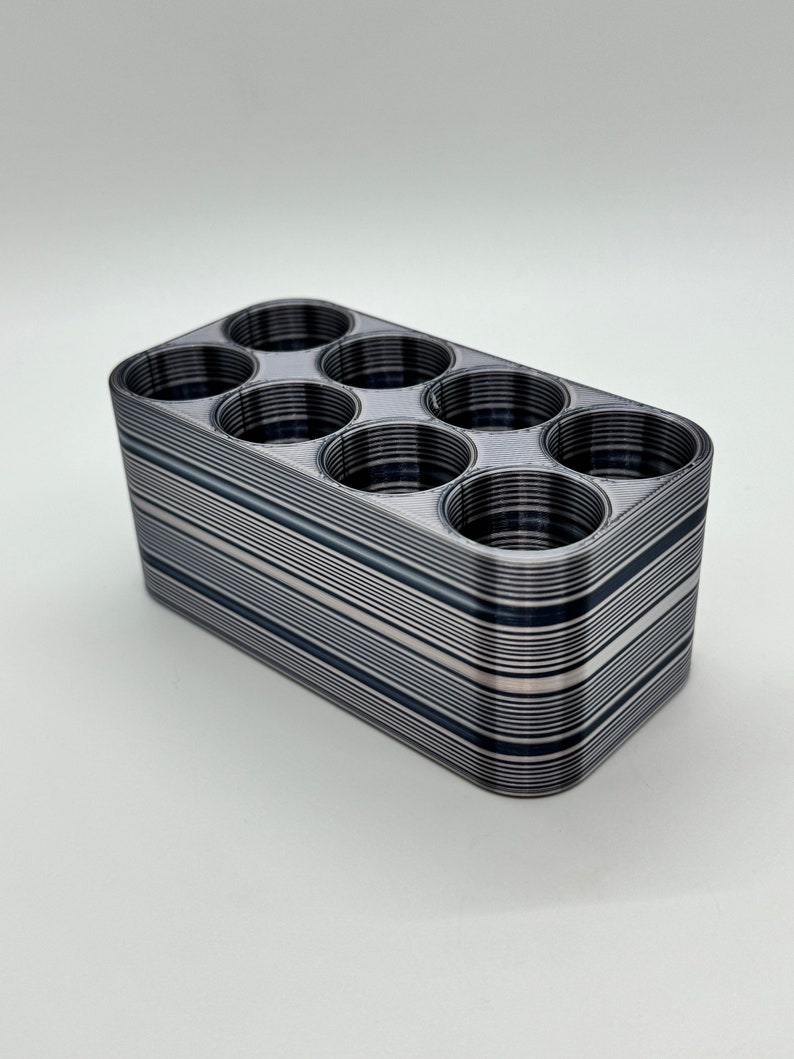May include: A black and white striped plastic organizer with eight round compartments.