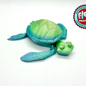 May include: A green and blue 3D printed sea turtle figurine with a closed shell. The turtle has a detailed face with closed eyes.
