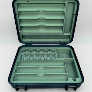 May include: An open blue carrying case with a green interior. The case has multiple compartments for storing pens and other writing instruments. The case is labeled "7 Pen Configuration".