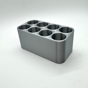 May include: A gray plastic organizer with six round compartments. The organizer is designed to hold small items, such as pens, pencils, or other office supplies.