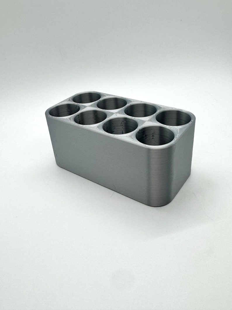May include: A gray plastic organizer with six round compartments. The organizer is designed to hold small items, such as pens, pencils, or other office supplies.