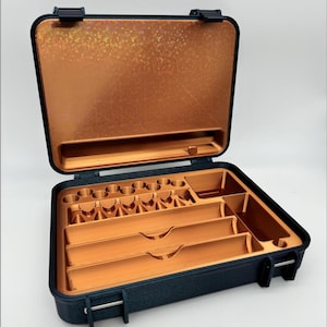 May include: A black hard-shell case with a copper-colored interior. The case has multiple compartments and slots for organizing small items. The lid of the case has a textured, iridescent surface.