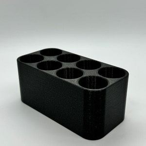 May include: A black plastic organizer with six round compartments. The organizer is designed to hold small items, such as pens, pencils, or other office supplies.