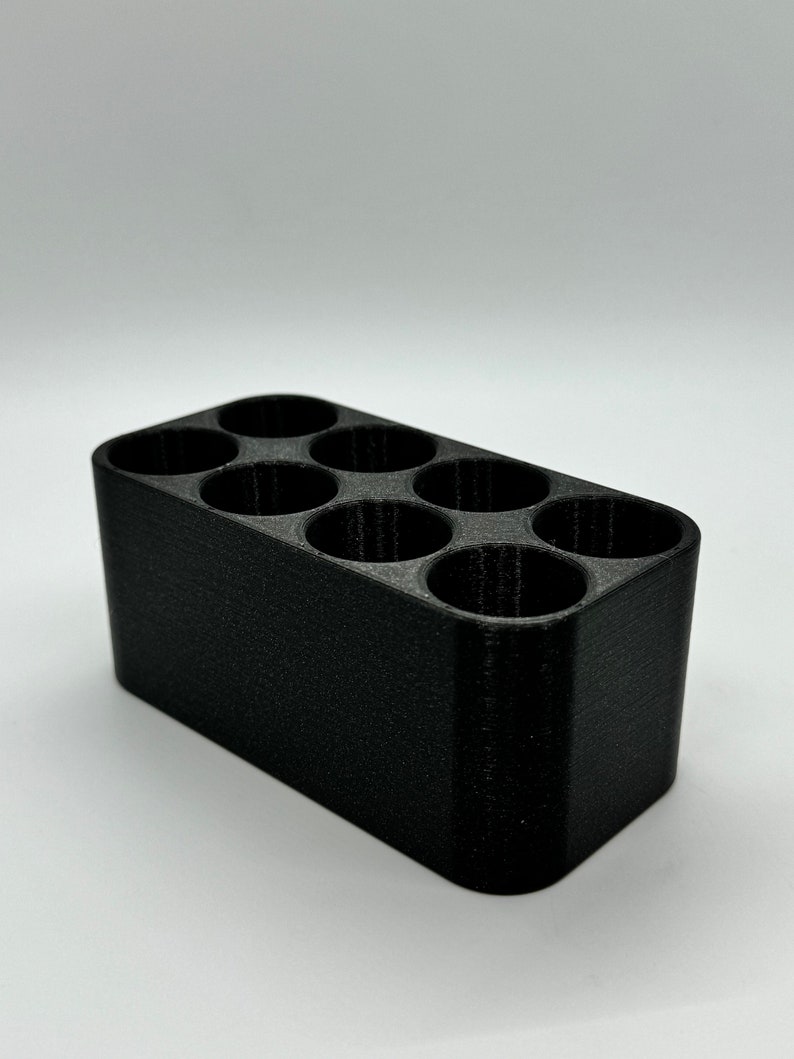 May include: A black plastic organizer with six round compartments. The organizer is designed to hold small items, such as pens, pencils, or other office supplies.