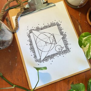 May include: A black and white line drawing of geometric shapes, including a sphere, a cone, and a cube, surrounded by a border of small flowers. The drawing is on a white sheet of paper.