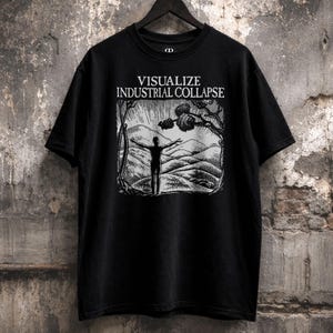 Könnte beinhalten: Schwarzes T-Shirt mit dem Text "VISUALIZE INDUSTRIAL COLLAPSE" über einer Schwarz-Weiß-Grafik einer Person mit erhobenen Armen in einer Landschaft. Das T-Shirt hängt an einem schwarzen Kleiderbügel vor einer strukturierten Wand.