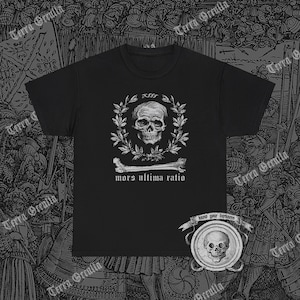 May include: Black t-shirt with a white skull and crossbones graphic. The graphic features a skull with a laurel wreath around it and the text "mors ultima ratio". The shirt also has a small patch with the text "know your darkness" and a skull graphic.
