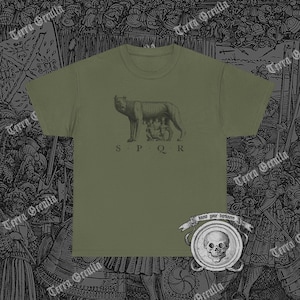 May include: A green t-shirt with a black and white illustration of a wolf with the letters "SPQR" underneath. The t-shirt has a skull and crossbones design on the bottom right corner with the text "know your darkness".