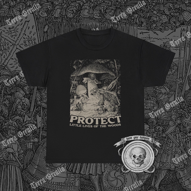 May include: Black t-shirt with a graphic print featuring a toad, mushroom, and skull scene. The word "PROTECT" is printed above "LITTLE LIVES OF THE WOODS". The shirt has a crew neck and short sleeves.