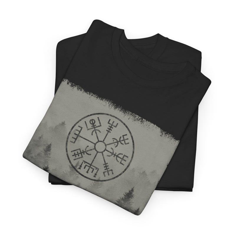 Może przedstawiać: Czarny t-shirt z szarym i białym wzorem przedstawiającym kompas na tle lasu.