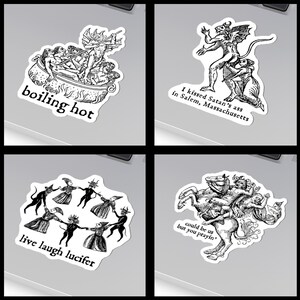 May include: Four black and white stickers with gothic illustrations. One shows figures in a cauldron with the text "boiling hot." Another depicts a devilish figure with the text "I kissed Satan's ass in Salem, Massachusetts." The third shows figures dancing with the text "live laugh lucifer." The last shows figures on a horse with the text "could be us but you prayin'."