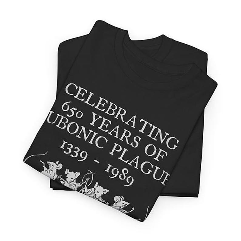 Puede incluir: Camiseta negra con texto blanco que dice "Celebrating 650 Years of Bubonic Plague 1339 - 1989". La camiseta presenta un peque&ntilde;o gr&aacute;fico de ratones.