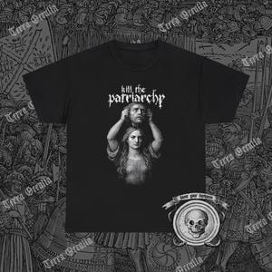 Può includere: T-shirt nera con una grafica raffigurante una donna che tiene una testa mozzata, con la scritta "kill the patriarchy" sopra. Un emblema circolare con un teschio e le parole "know your darkness" in basso.